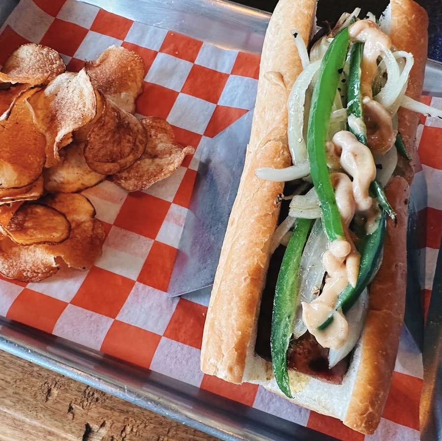Grilled kielbasa sandwich with queso, tomatoes and jalapeños with house chips