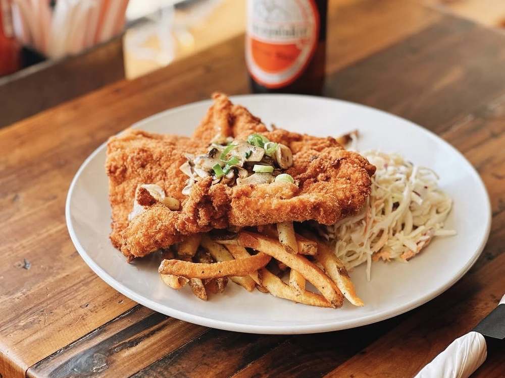 Crispy breaded schnitzel with sautéed mushrooms, coleslaw and fries at Spoko